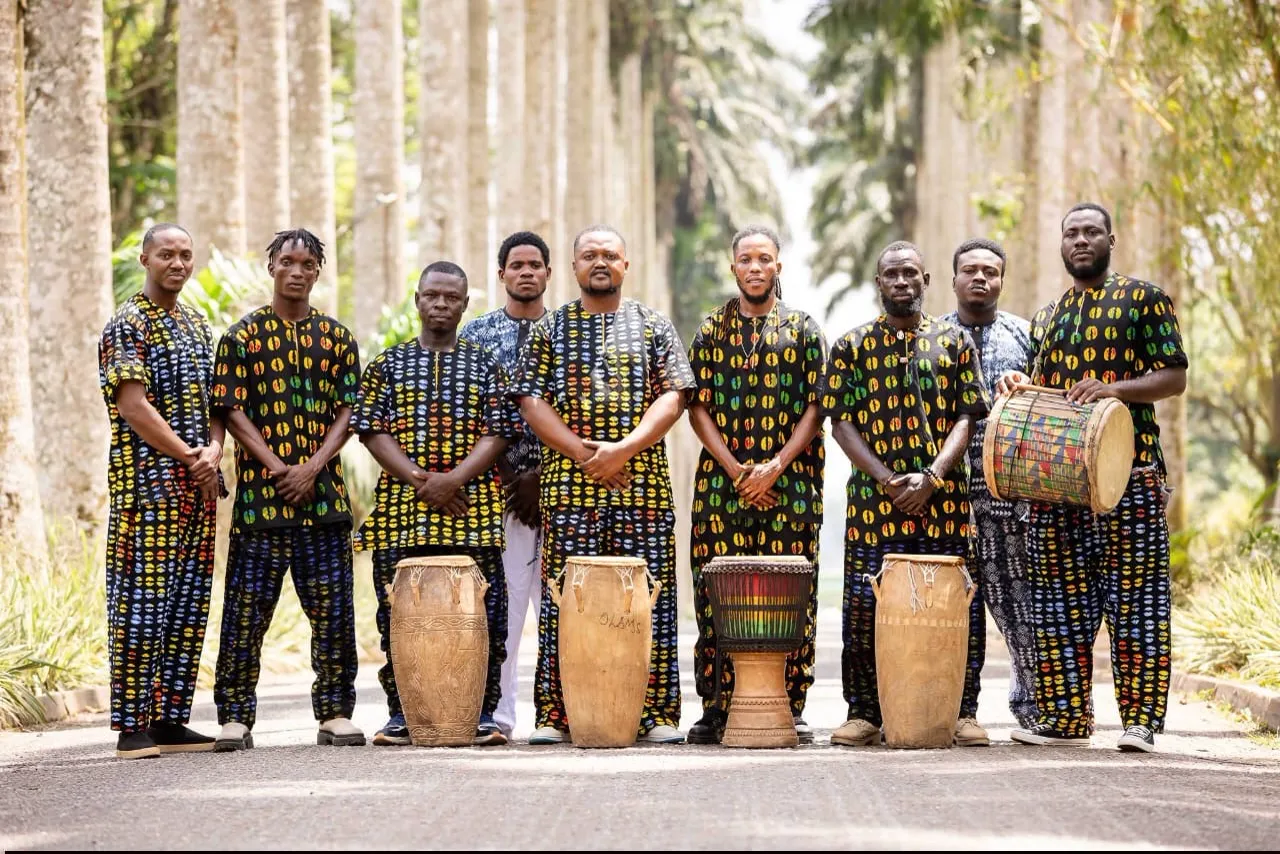 Members of Nyanyano Cultural Troupe standing with drums along a palm avenue